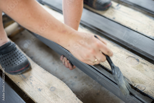 Painting boards with a brush held in hand. Gray, anthracite wood paint.