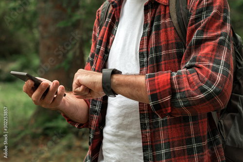 Hiker connecting smartwatch to smartphone to synchronize the data © Bits and Splits