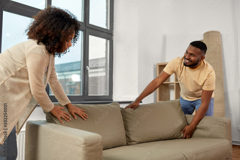 moving, people, repair and real estate concept - happy african american couple with sofa at new home moving, people, repair and real estate concept - happy african american couple with sofa at new home