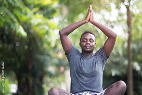 African man is meditating on green grass in the park © arrowsmith2