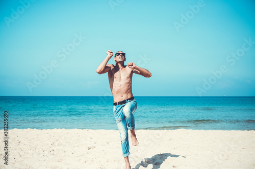 young muscular man resting and posing on the beach. Jump in the air
