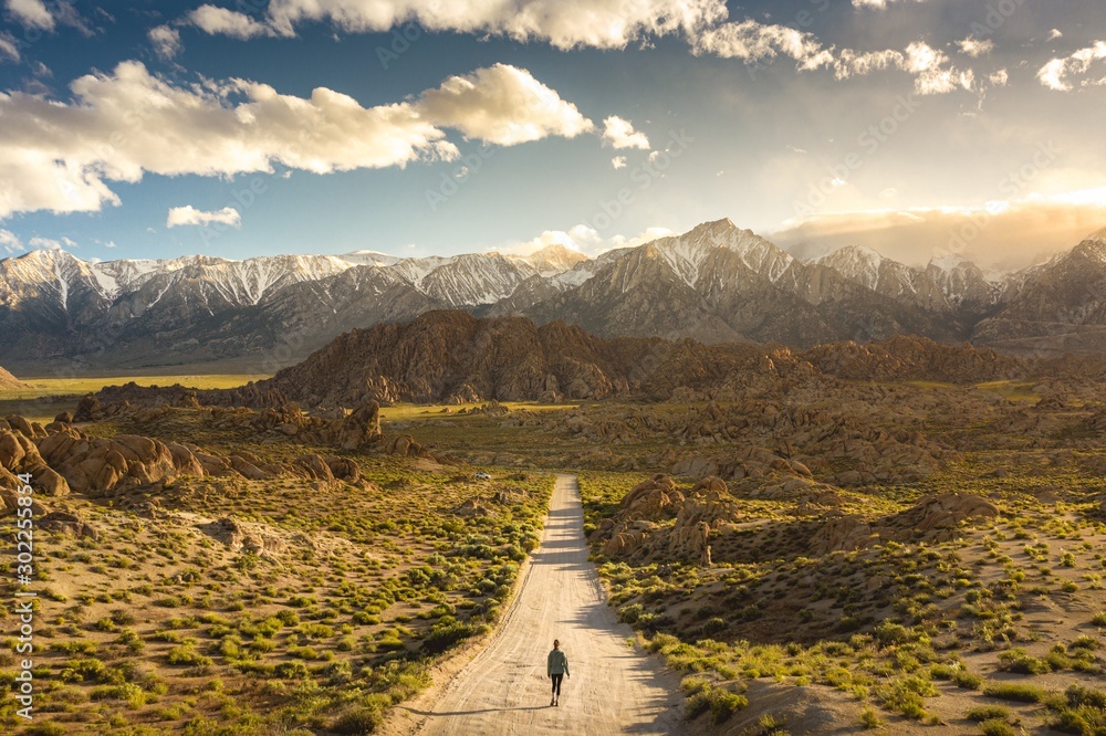 Lonely person walking on a pathway in Alabama hills in California with Mount Whitney in background - obrazy, fototapety, plakaty 