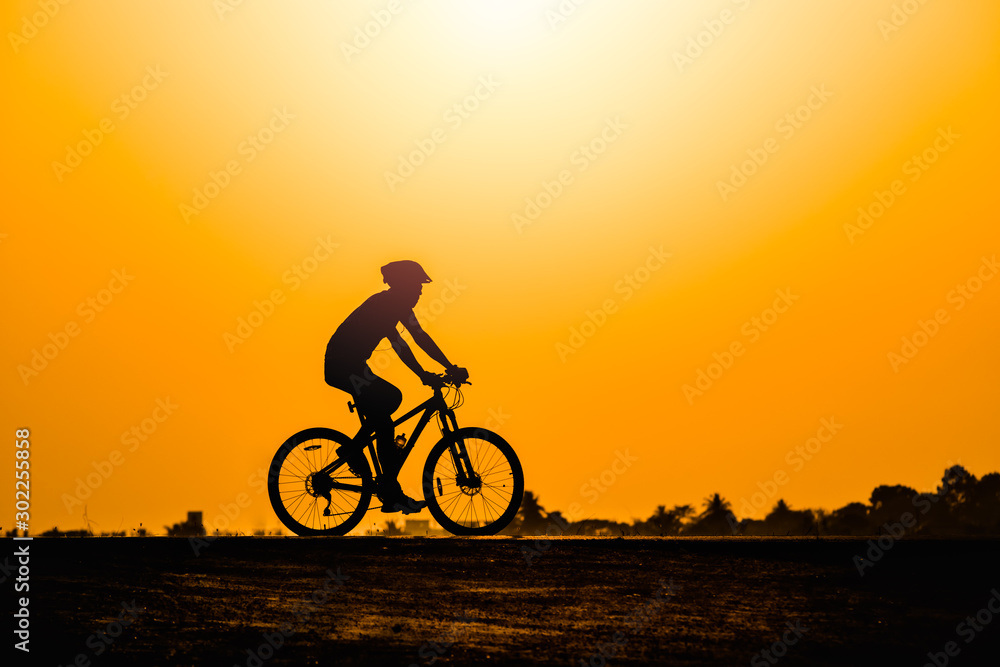 Obraz premium Silhouette man cycling on sunset background