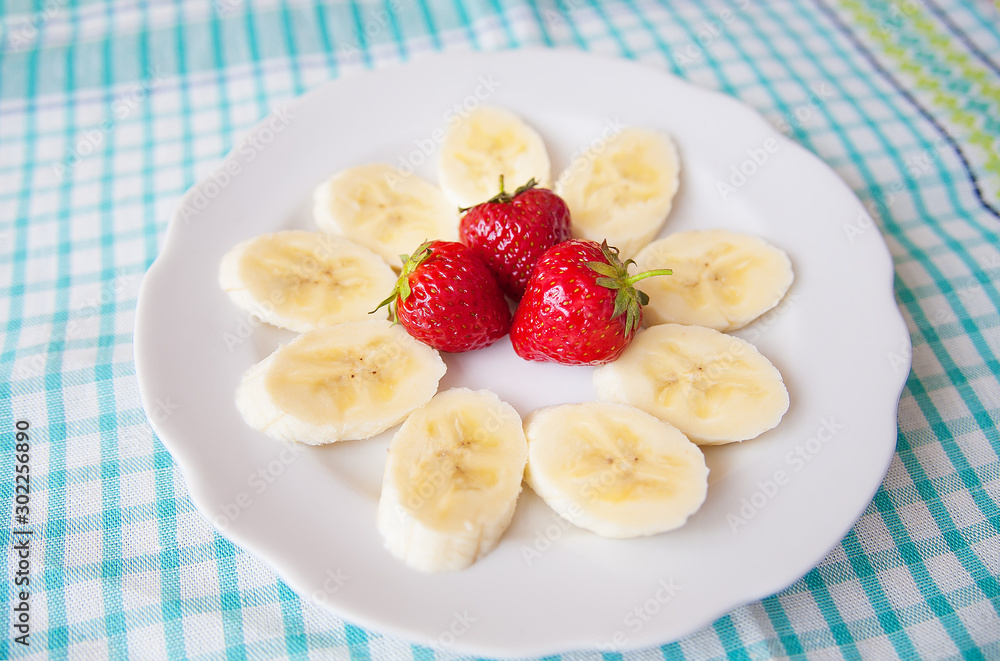 banana and strawberries on white plate and a colorful napkin banana and strawberries on white plate and a colorful napkin