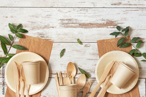 Eco friendly disposable dishes made of bamboo wood and paper on white wooden background. photo