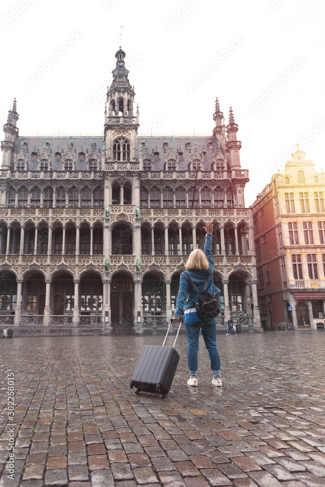 Obraz premium Woman tourist goes with a suitcase at the Grand Place in Brussels, Belgium