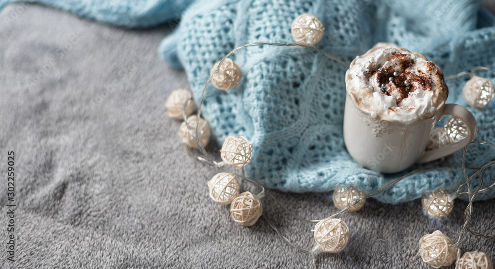 cozy winter composition with cup of hot chocolate, hot cooca cup with knitted sweater and ball lights, girly winter aesthetic photography, banner background with copyspace