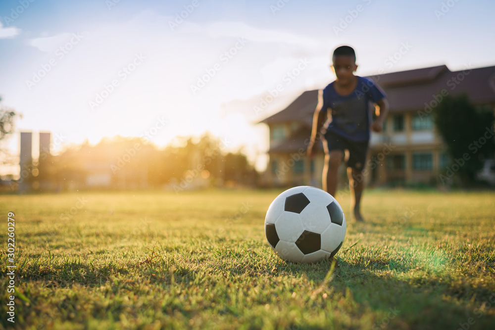 Φωτογραφία Action sport outdoors of kids having fun playing soccer football for exercise in community rural area under the twilight sunset sky