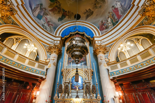 Vintage candlesticks under the dome of the catholic church with paintings and antique decoration. 17th century Roman Catholic church on Malta photo