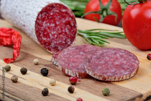 Salami with cherry tomatoes, rosemary, chilli and colorful peppercorns on table