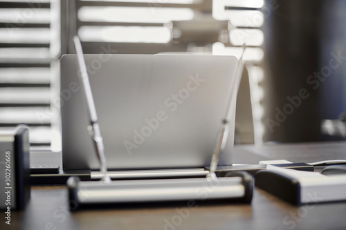 Modern office workplace. Business laptop in work place for chief, boss or other employees. Notebook on work table. Office large corporation. Light through half open blinds