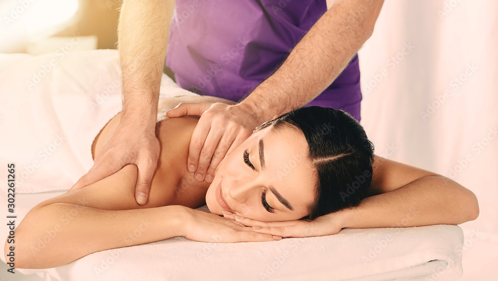 Brunette woman enjoying relaxing back massage at wellness resort. Woman pampering her body at spa Brunette woman enjoying relaxing back massage at wellness resort. Woman pampering her body at spa