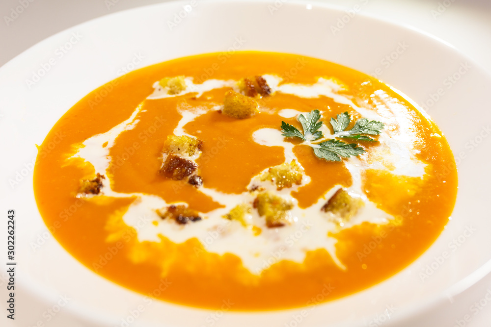 Pumpkin and carrot soup with cream, toasts and parsley