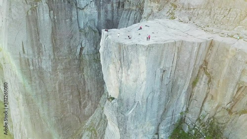 A drone flight over the Lysefjorden, in the area of Preikestolen, Norway. A man in a blue shirt walks on the rocks at the edge of the fjord. Hiking remedy, that gives you a lot of freedom. 