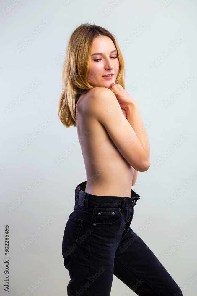 picture of beautiful topless woman in jeans covering breasts with hands on gray background picture of beautiful topless woman in jeans covering breasts with hands on gray background