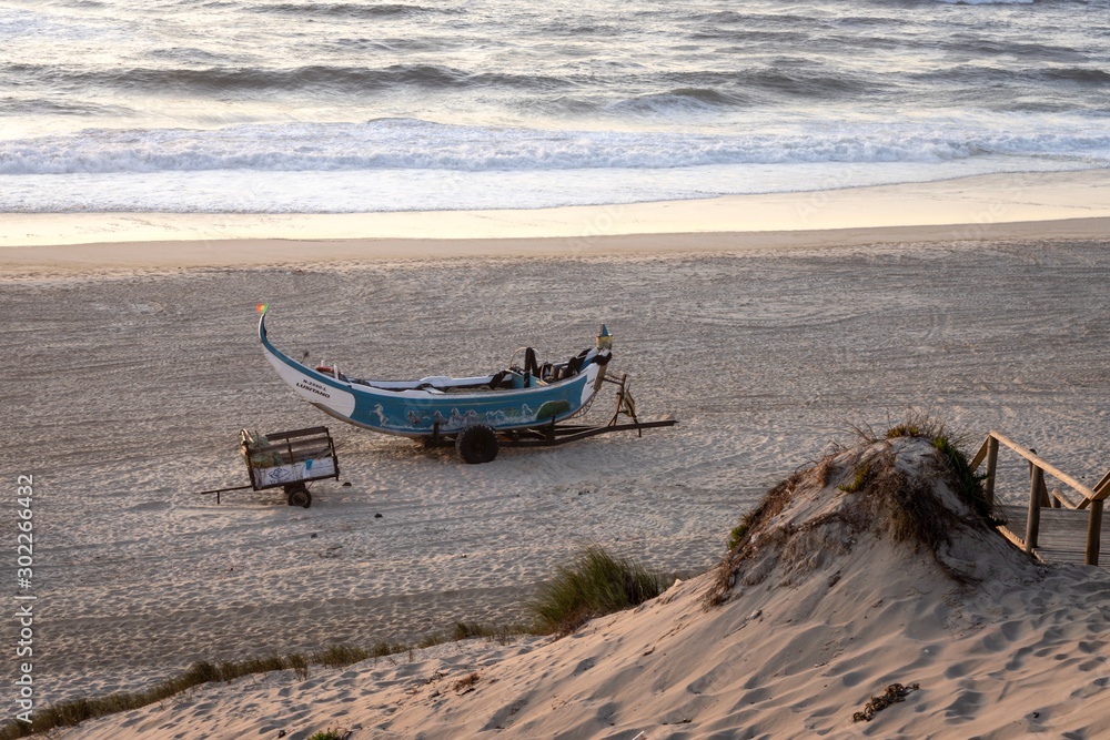 Small and old fishing boat standing on the sand in the golden hour
