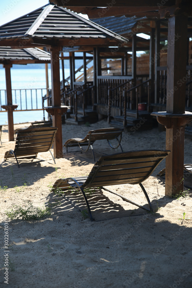 Wooden sunbeds and umbrellas on a deserted beach in low season. Wooden sunbeds and umbrellas on a deserted beach in low season.