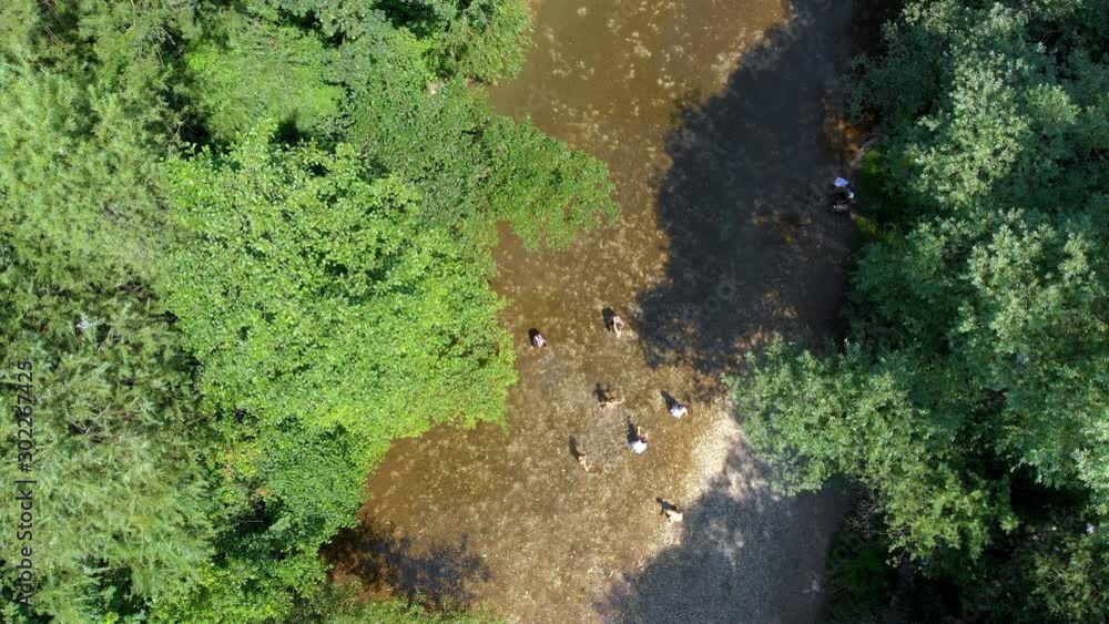 Children are sprinkling each other with water in the middle of a river. Aerial shot. It's a nice and sunny day. Children are sprinkling each other with water in the middle of a river. Aerial shot. It's a nice and sunny day.