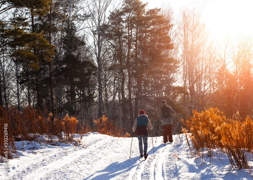 A couple of young people go cross-country skiing on a beautiful winter evening.