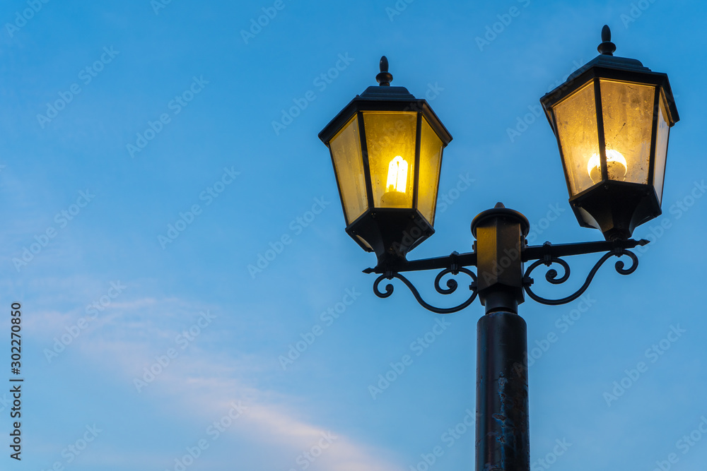 The yellow light of the street lamp has a beautiful blue sky background