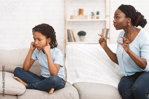 African-american mother telling off her daughter closing ears