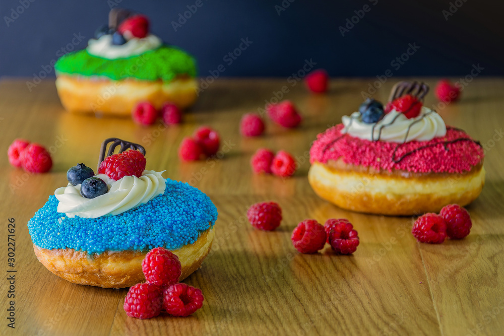 delicious donuts with raspberries on wooden table delicious donuts with raspberries on wooden table