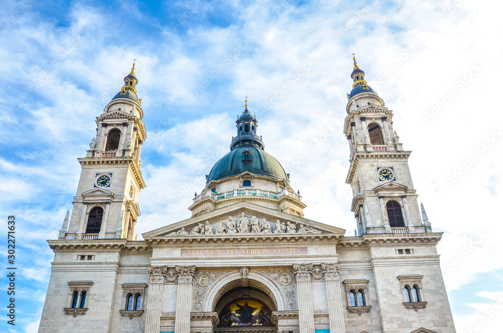 Front facade of St. Stephen's Basilica in Budapest, Hungary on with blue sky and clouds above. Roman Catholic basilica built in neoclassical style. Two towers and cupola of the religious building