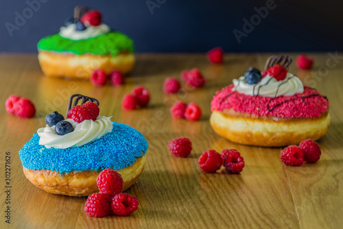delicious donuts with raspberries on wooden table