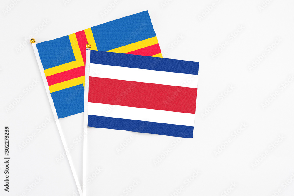 Costa Rica and Aland Islands stick flags on white background. High quality fabric, miniature national flag. Peaceful global concept.White floor for copy space. Costa Rica and Aland Islands stick flags on white background. High quality fabric, miniature national flag. Peaceful global concept.White floor for copy space.