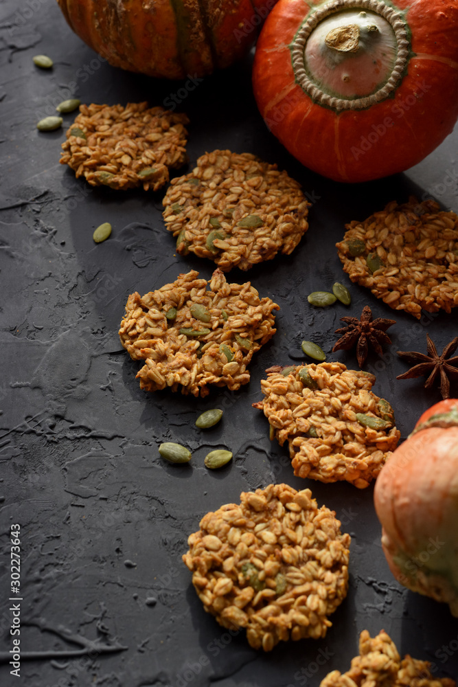 Healthy vegan gluten free food. Homemade pumpkin oatmeal breakfast cookies with seeds and turban squash on black background Healthy vegan gluten free food. Homemade pumpkin oatmeal breakfast cookies with seeds and turban squash on black background
