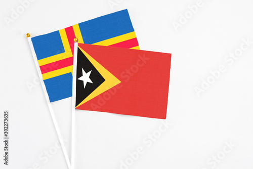 Free Download East Timor and Aland Islands stick flags on white background. High quality fabric, miniature national flag. Peaceful global concept.White floor for copy space. - GFXLoad