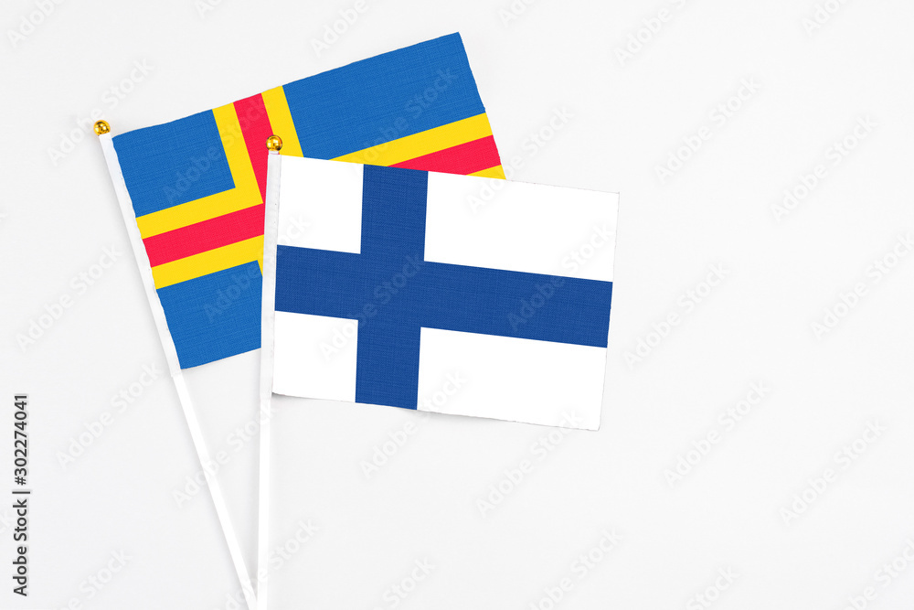 Finland and Aland Islands stick flags on white background. High quality fabric, miniature national flag. Peaceful global concept.White floor for copy space.
