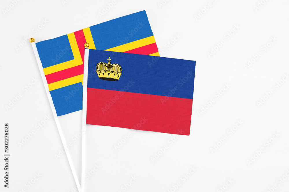 Liechtenstein and Aland Islands stick flags on white background. High quality fabric, miniature national flag. Peaceful global concept.White floor for copy space. Liechtenstein and Aland Islands stick flags on white background. High quality fabric, miniature national flag. Peaceful global concept.White floor for copy space.