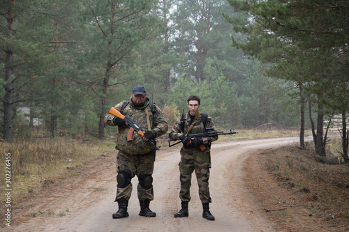 Two soldier with assault rifle in uniform patrolling territory outdoors