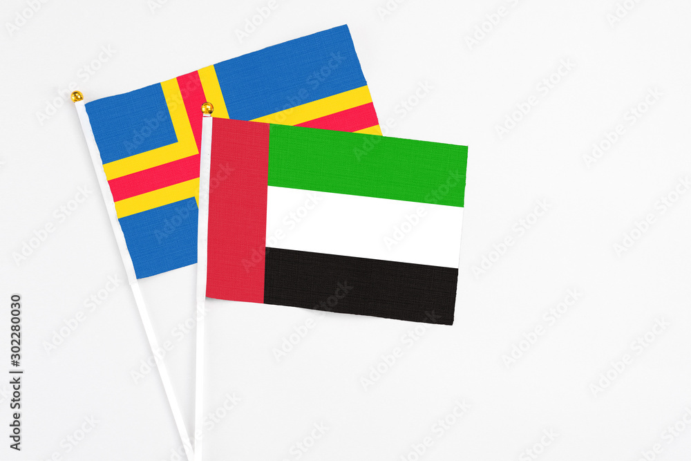 United Arab Emirates and Aland Islands stick flags on white background. High quality fabric, miniature national flag. Peaceful global concept.White floor for copy space. United Arab Emirates and Aland Islands stick flags on white background. High quality fabric, miniature national flag. Peaceful global concept.White floor for copy space.