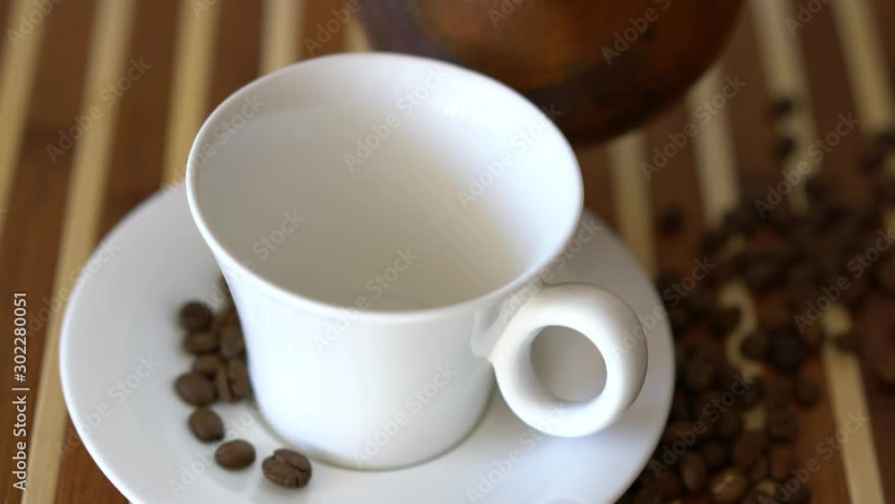 Arabic coffee is poured into a white cup. Arabic coffee is poured into a white cup.