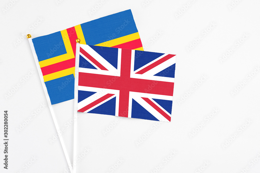 Fototapeta premium United Kingdom and Aland Islands stick flags on white background. High quality fabric, miniature national flag. Peaceful global concept.White floor for copy space.
