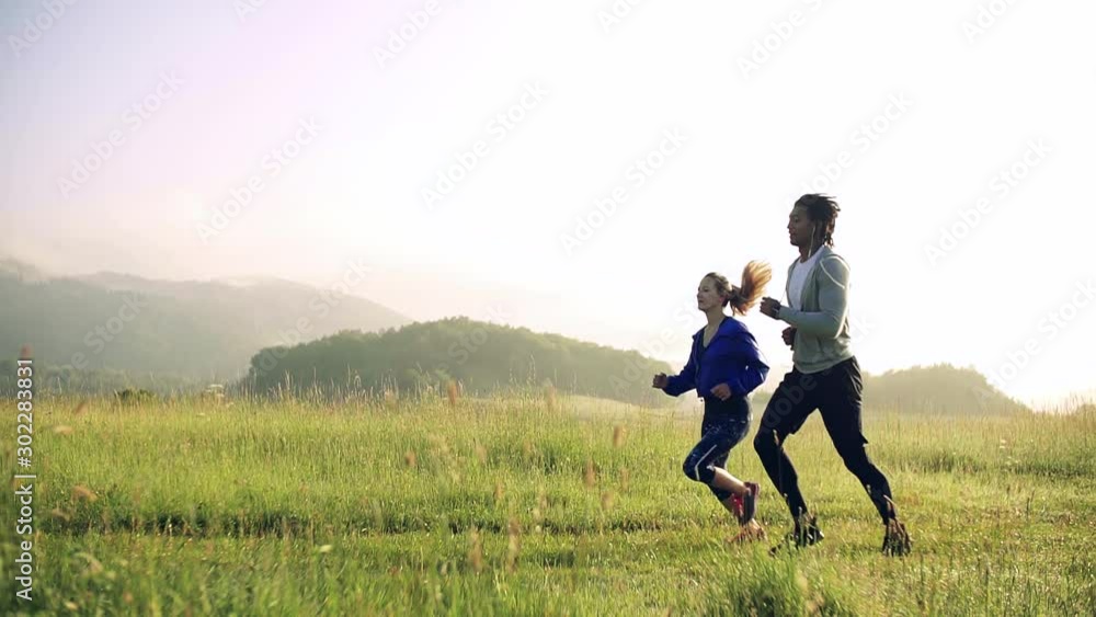 Young couple running on meadow outdoors in nature, in foggy morning. Young couple running on meadow outdoors in nature, in foggy morning.