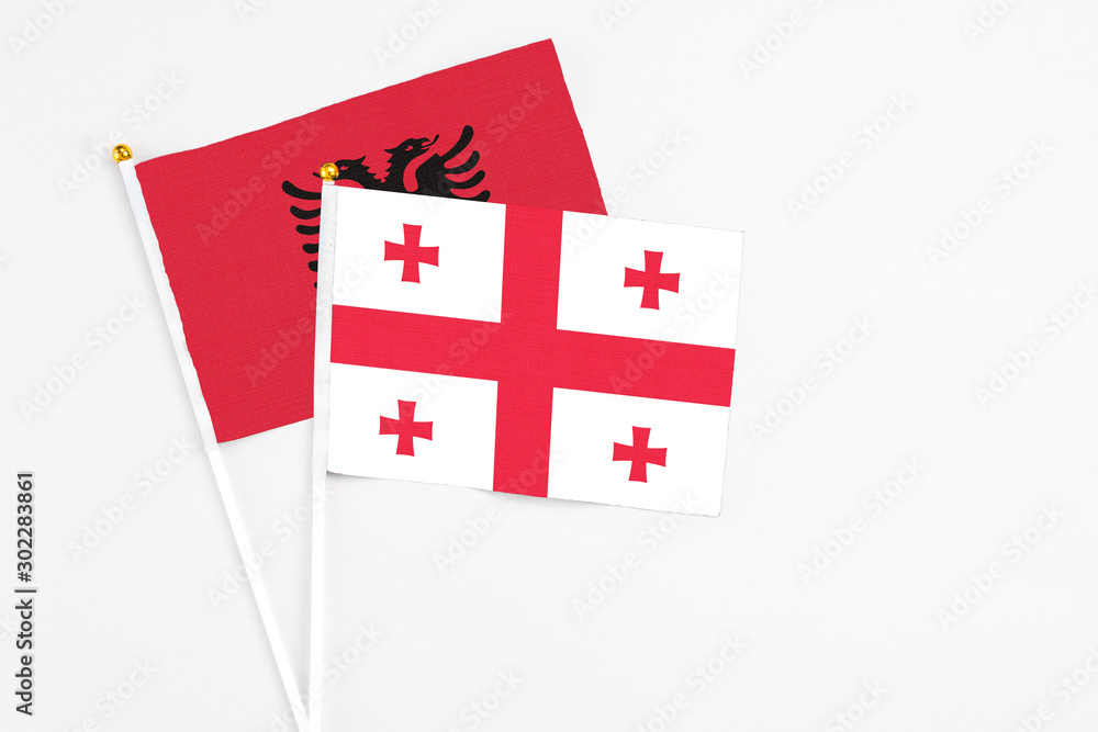 Georgia and Albania stick flags on white background. High quality fabric, miniature national flag. Peaceful global concept.White floor for copy space.