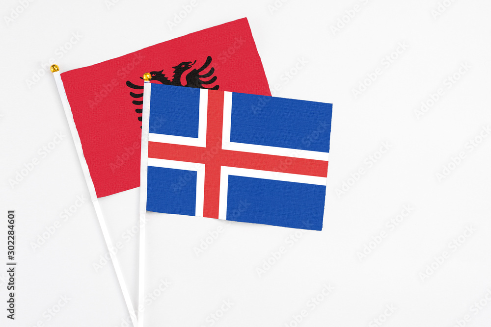 Iceland and Albania stick flags on white background. High quality fabric, miniature national flag. Peaceful global concept.White floor for copy space.