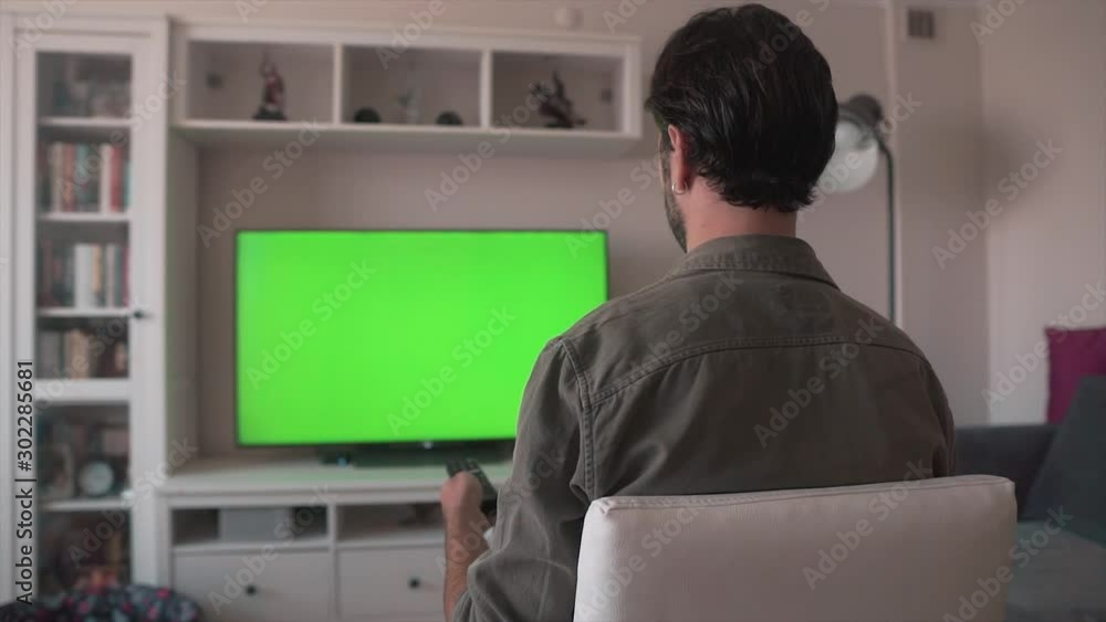 Man is watching TV in home alone. Television's screen is alpha channel, video mock up, green screen. Man is watching TV in home alone. Television's screen is alpha channel, video mock up, green screen.