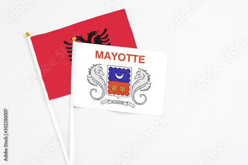 Mayotte and Albania stick flags on white background. High quality fabric, miniature national flag. Peaceful global concept.White floor for copy space.