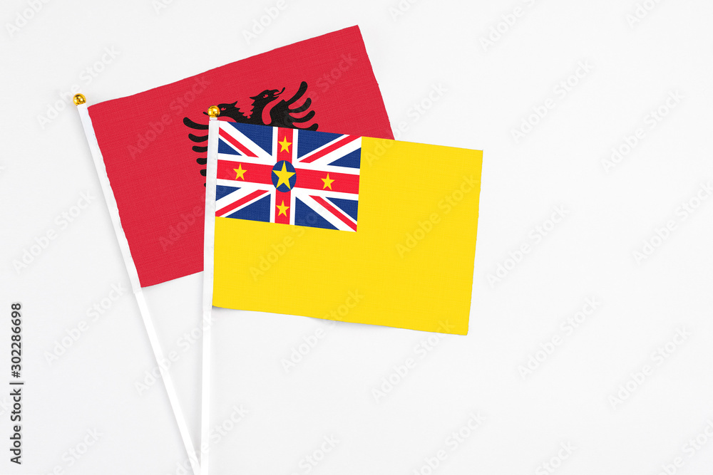 Niue and Albania stick flags on white background. High quality fabric, miniature national flag. Peaceful global concept.White floor for copy space. Niue and Albania stick flags on white background. High quality fabric, miniature national flag. Peaceful global concept.White floor for copy space.