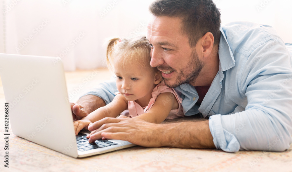 Millennial father and daughter using laptop together Millennial father and daughter using laptop together