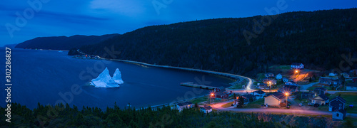 Iceberg in harbor of small village at twilight in Newfoundland photo