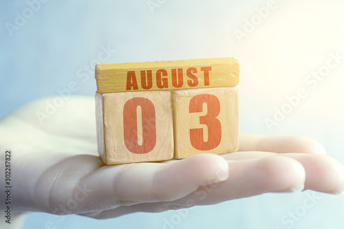 august 3rd. Day 3 of month,Handmade wood cube with date month and day on female palm summer month, day of the year concept
