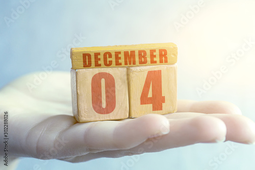 december 4th. Day 4 of month,Handmade wood cube with date month and day on female palm winter month, day of the year concept