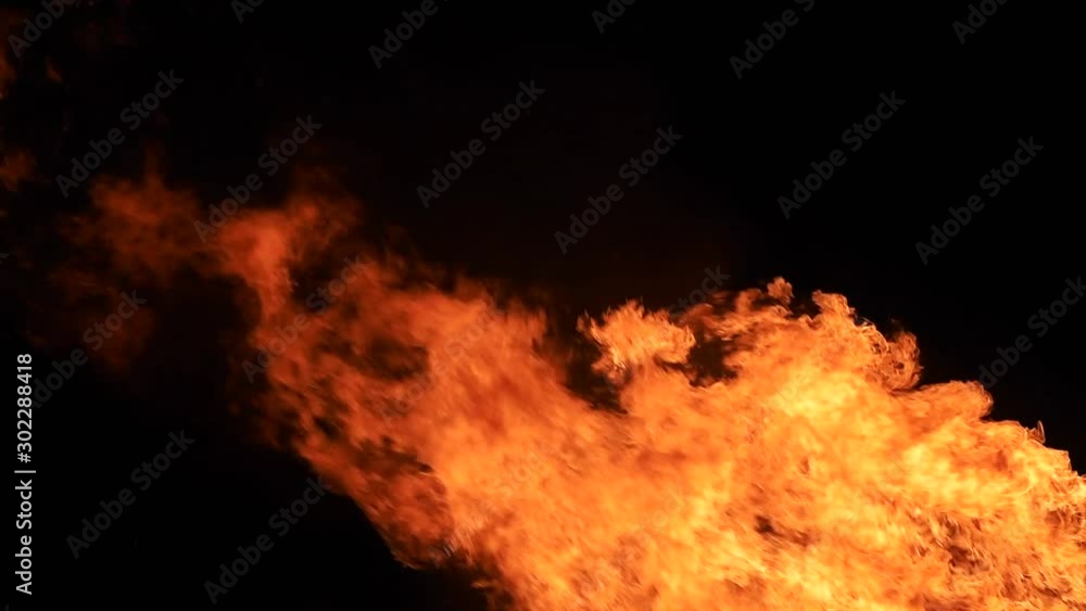 Close up shot of raging wild red fire flames against night sky with heat haze.