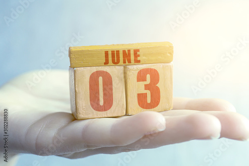 june 3rd. Day 3 of month,Handmade wood cube with date month and day on female palm summer month, day of the year concept