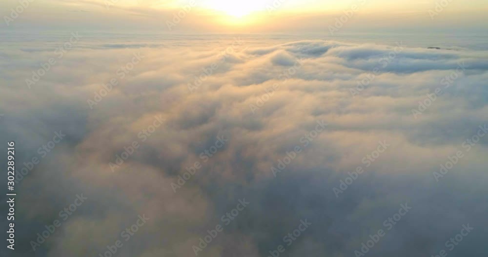 Drone flying over the clouds at sunset. The sun is hidden behind the clouds at sunset fog. Drone flying over the clouds at sunset. The sun is hidden behind the clouds at sunset fog.